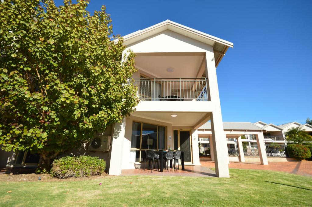a white house with a balcony and a yard at Pelican Shore Villa 11- Kalbarri WA in Kalbarri