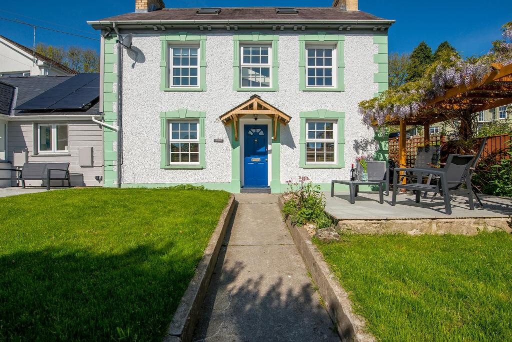 una casa bianca con una porta blu e un cortile di Llys Bonfyl a Cardigan