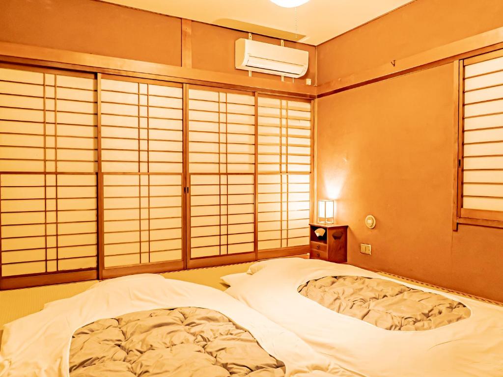 a bedroom with a large bed in a room with windows at The M OTAMACHI in Nakatsugawa