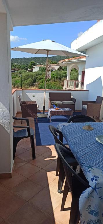 un patio con mesas y una sombrilla en el balcón en HAIKU HOME, en Cala Gonone