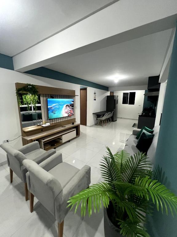 a living room with a couch and a tv at Summer Apartment in Porto De Galinhas