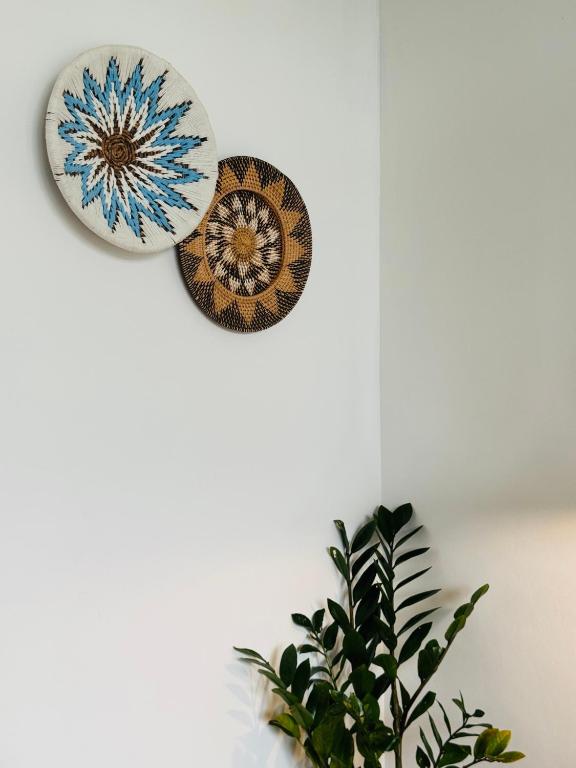 two plates hanging on a wall next to a plant at Whãnau villa 1 in Cemagi