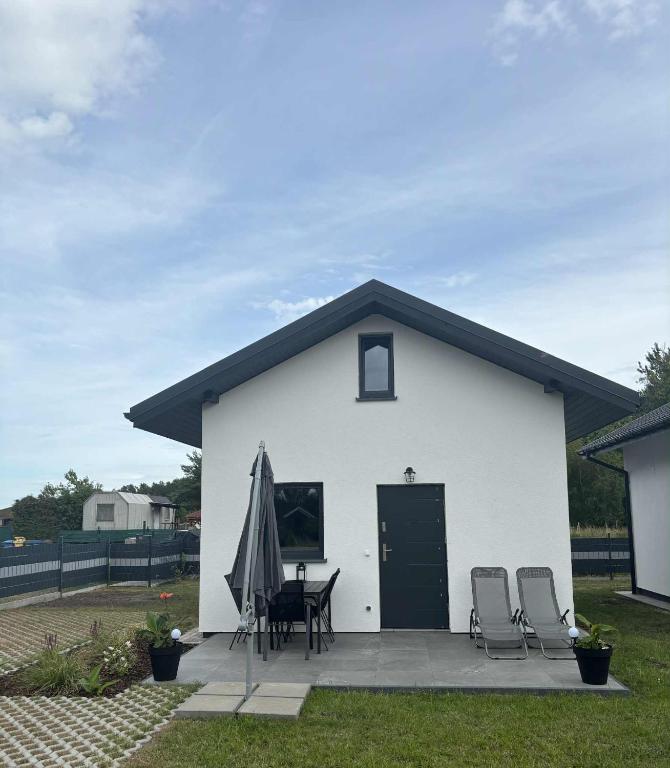 a white building with a table and chairs and an umbrella at Domki M&M in Kołczewo