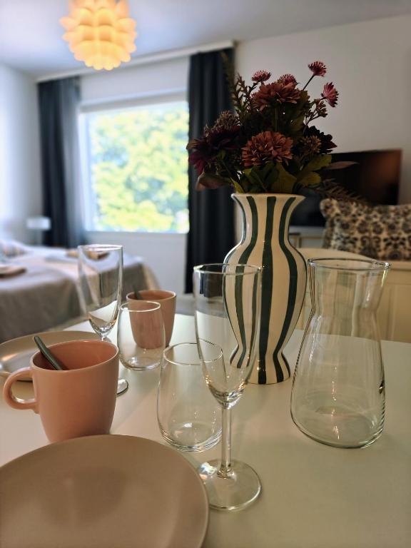 a table with glasses and a vase with flowers in it at Kampuksen Hertta in Pori