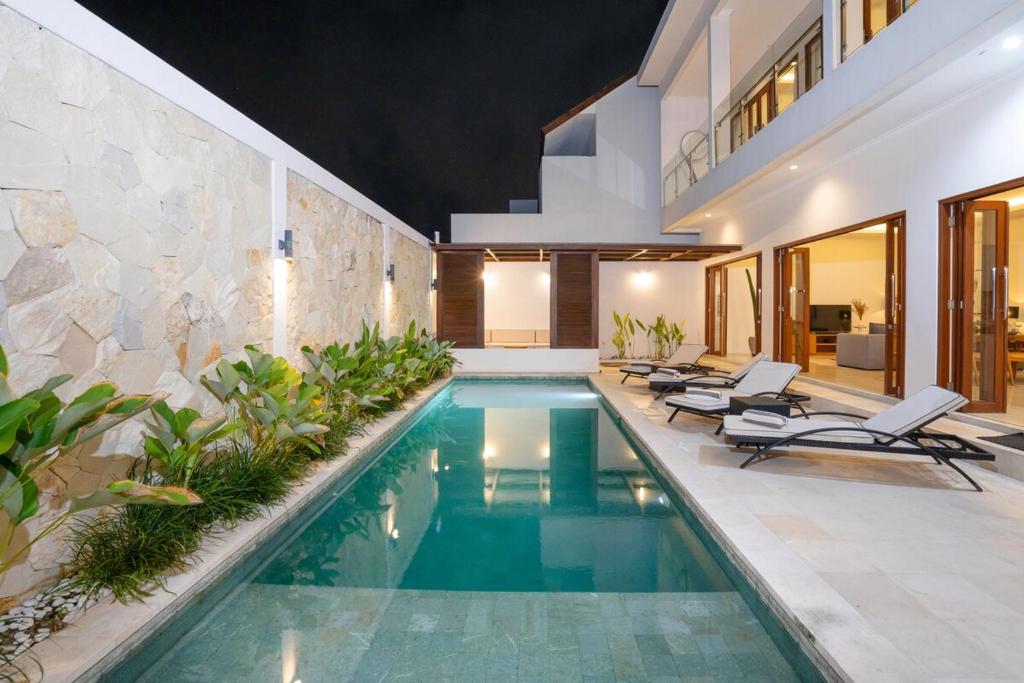 a swimming pool in a villa with lounge chairs at Cosy and Luxurious Villa Sentosa Seminyak in Seminyak