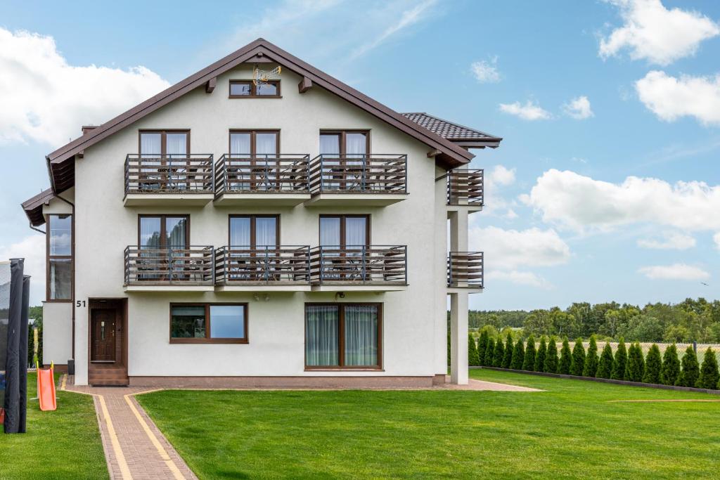 a large white house with a green lawn at Komfort i spokój blisko natury - Apartamenty i pokoje ARKO in Ostrowo