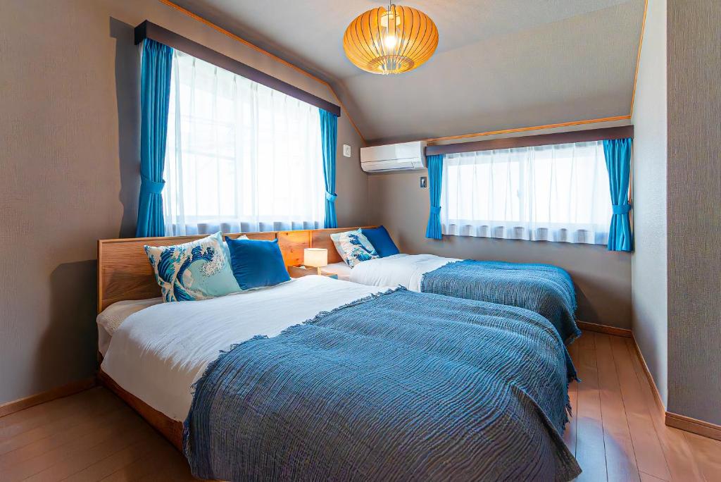two beds in a bedroom with blue curtains at Third Place Tokyo - Aoto - in Tokyo