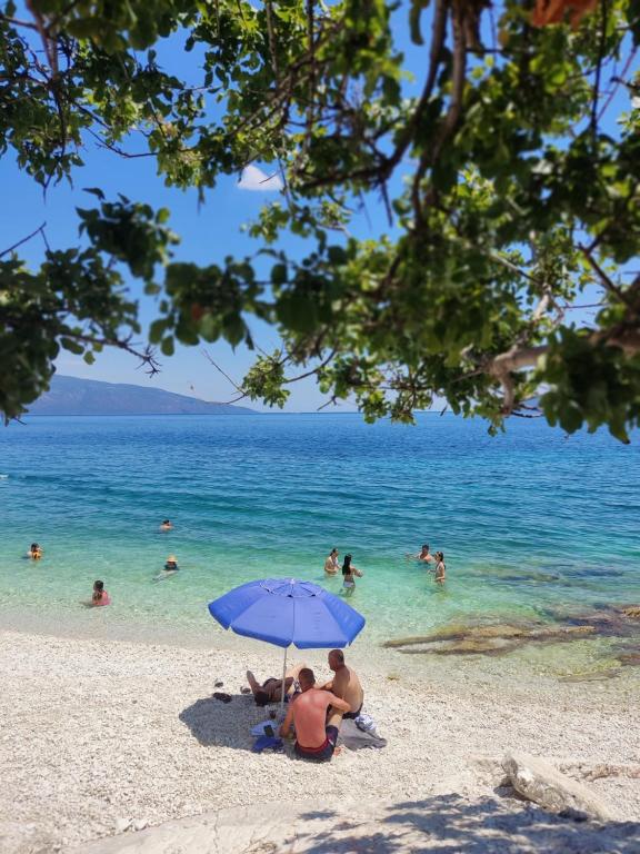 two people sitting under an umbrella on a beach at Chloe attic in Agia Effimia