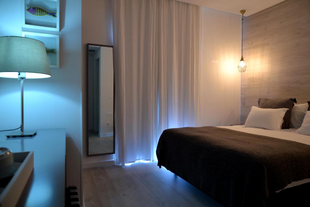 a bedroom with a bed and a mirror and a lamp at Hotel Mar Bravo in Nazaré