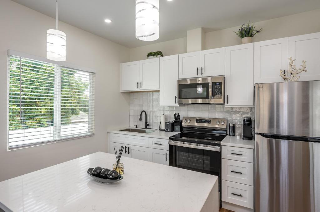 a kitchen with white cabinets and a stainless steel refrigerator at Modern home near Downtown San Diego in San Diego