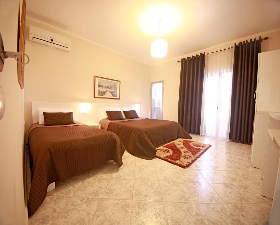 a bedroom with two beds and a window at Hotel Nika in Vlorë