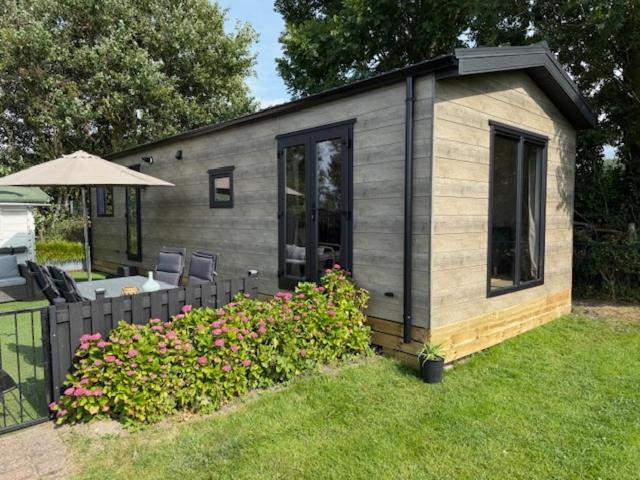 a small cabin with a fence and some flowers at Nieuw in 2025! Modern vakantiehuis aan de Waddenzee in Westerland