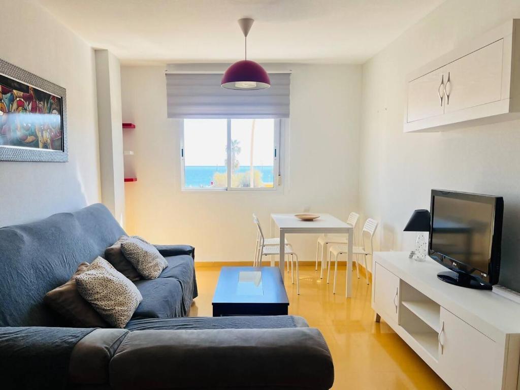 a living room with a blue couch and a table at Apartamento Romanilla Roquetas in Roquetas de Mar