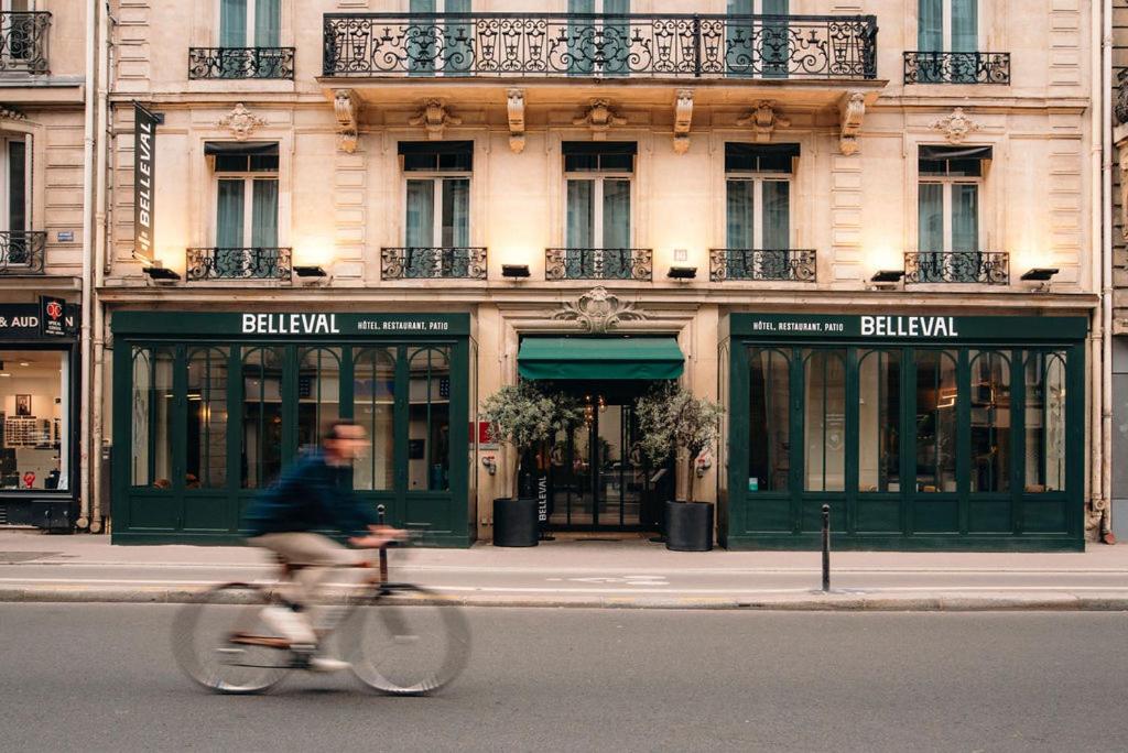 a man riding a bike in front of a building at Hôtel Belleval in Paris