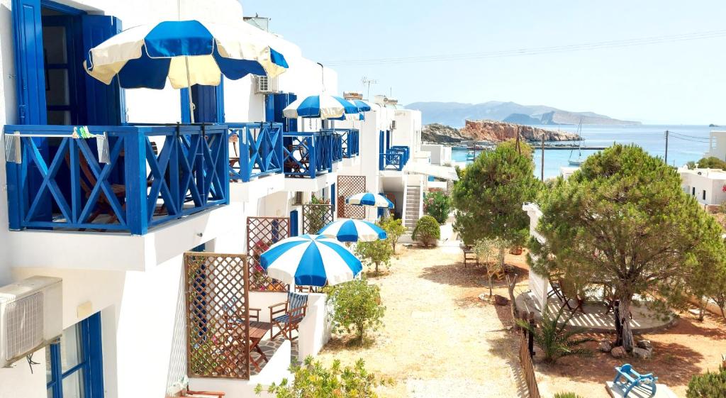 a balcony with blue and white buildings with umbrellas at Aegean Star Hotel in Karavostasi