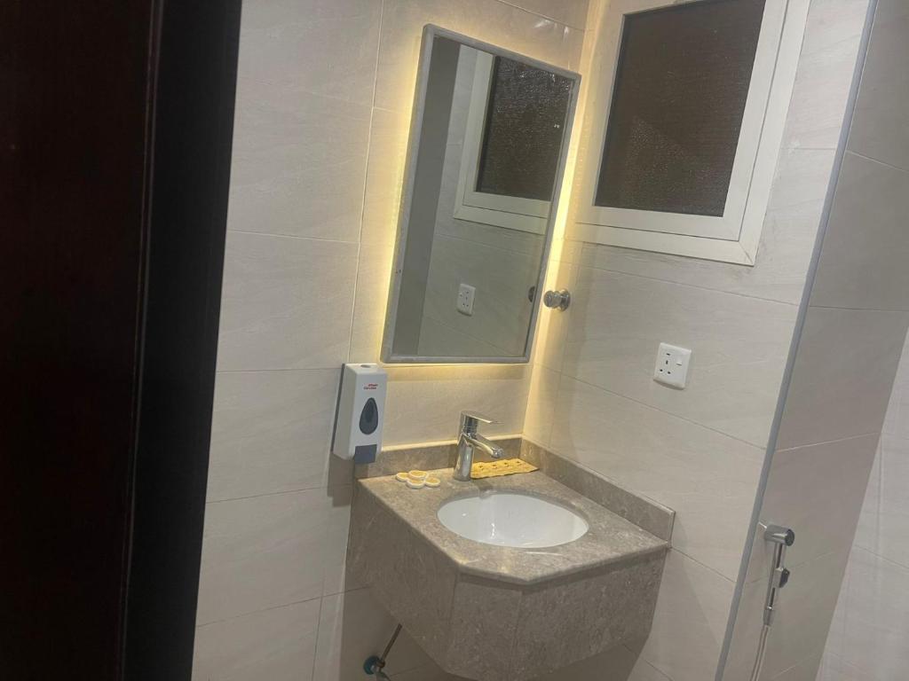 a bathroom with a sink with a mirror and a window at فندق عبير الفضيلة in Al Masfalah