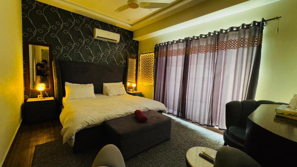 une chambre avec un grand lit et une chaise dans l'établissement Executive 1BHK with Scenic Balcony View & Free Netflix, à Rawalpindi