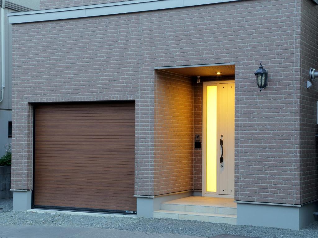 duas portas de garagem ao lado de um edifício de tijolos em Ocho Guest House em Sapporo