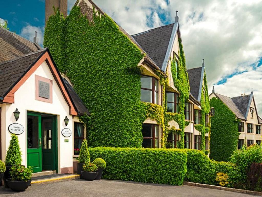 a ivy covered house with a green door at Oranmore Lodge Hotel Galway in Oranmore
