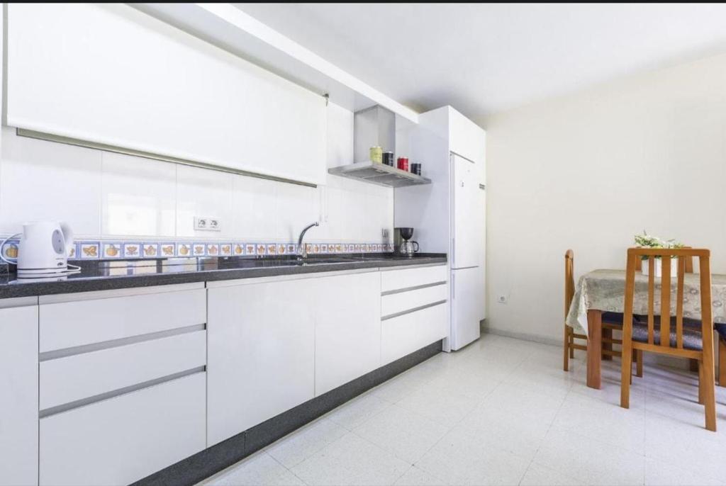 eine Küche mit weißen Schränken, einem Tisch und einem Stuhl in der Unterkunft Azucarera 2 Room- HOME RENT MALAGA in Torre del Mar
