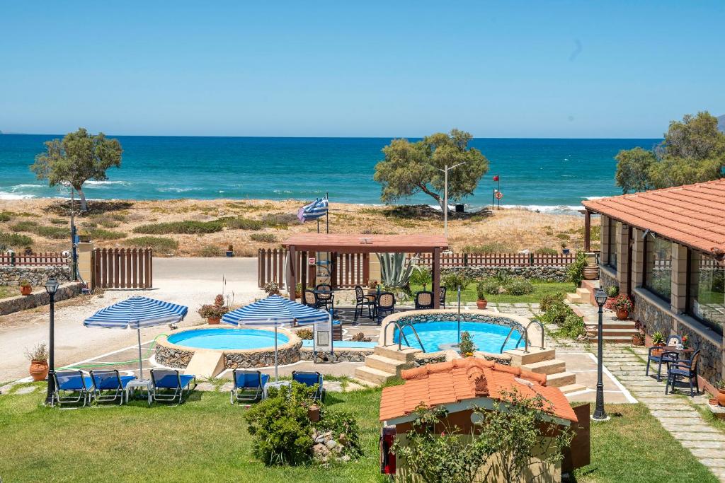 a resort with two pools and umbrellas and the beach at Drapanias BeachFront Apartments - Marinakis in Kissamos