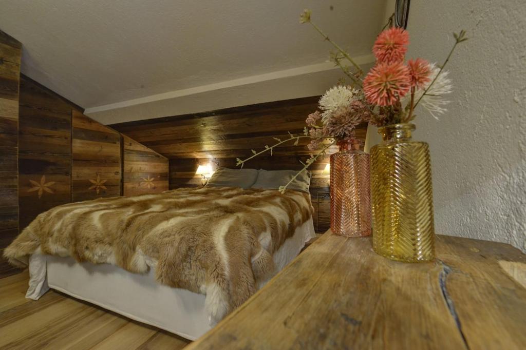ein Schlafzimmer mit einem Bett und zwei Vasen mit Blumen auf dem Tisch in der Unterkunft Charme Alpine in Morgex