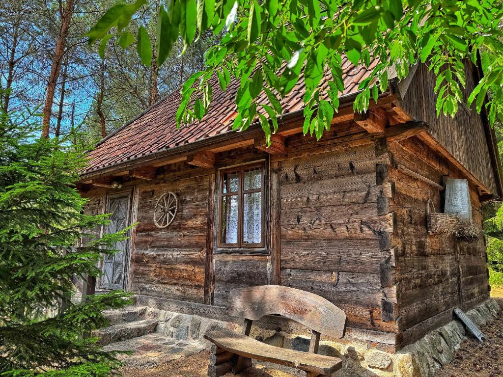 a log cabin with a bench in front of it at Mazurska Chatka in Zyzdrojowy Piecek