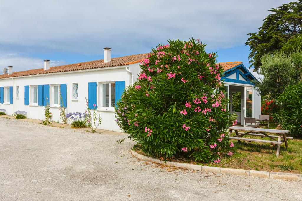 a house with a flowering bush in front of it at Maison d'hôtes Le Grillon in La Brée-les-Bains