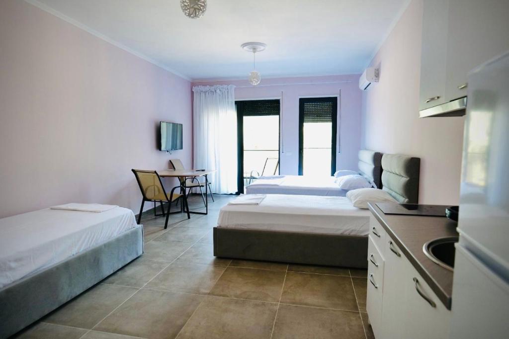 a bedroom with two beds and a kitchen and a table at Aren 1 in Vlorë