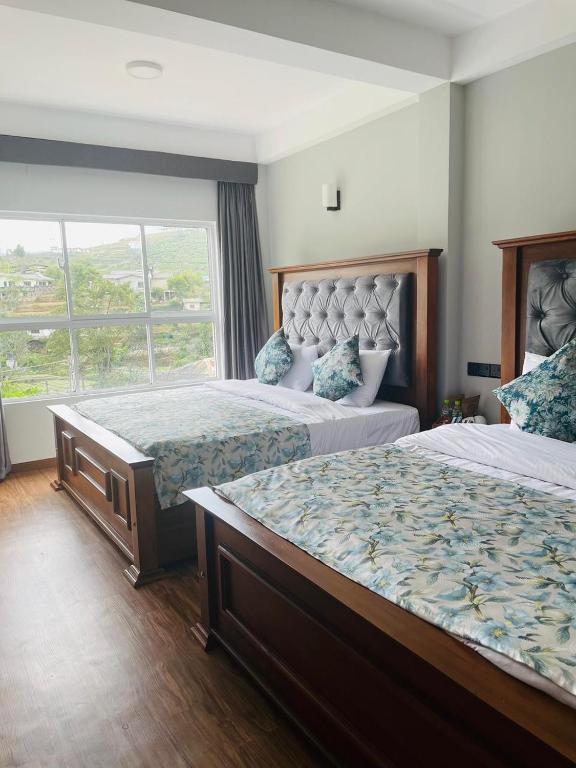 a hotel room with two beds and a window at Ambula Resort in Nuwara Eliya