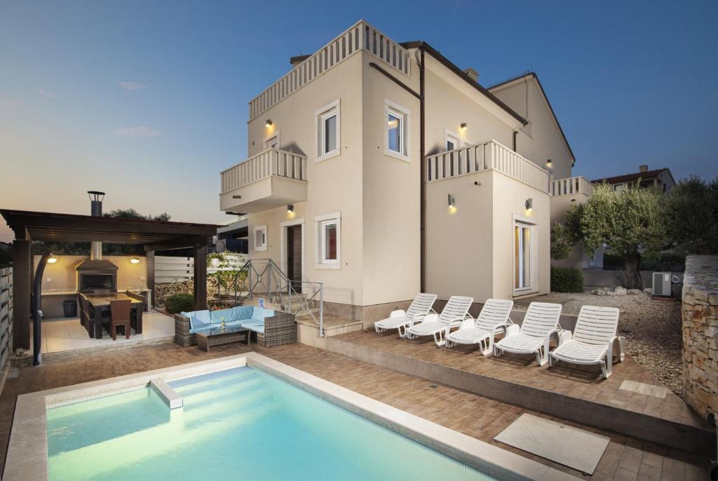 eine Villa mit einem Swimmingpool vor einem Haus in der Unterkunft Villa Castagna near the Sea with Private Pool and Sauna in Premantura