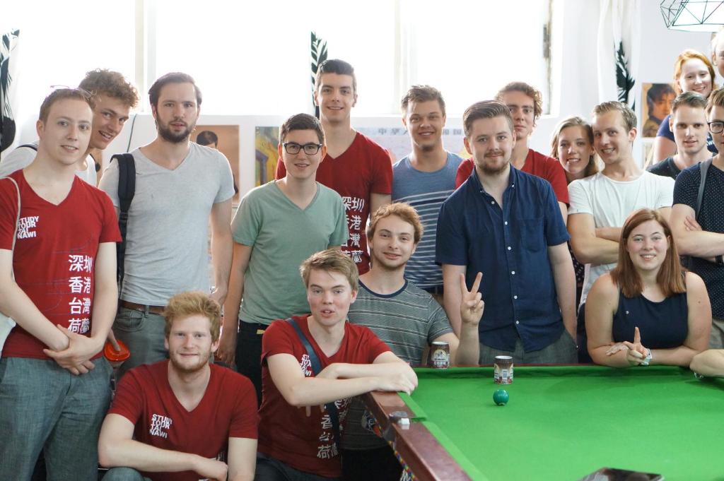 a group of people standing around a pool table at Notting Hill Hostel in Bao'an