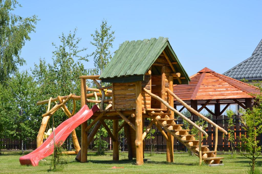 a wooden playground with a slide and a house at Zacisze in Rozalin