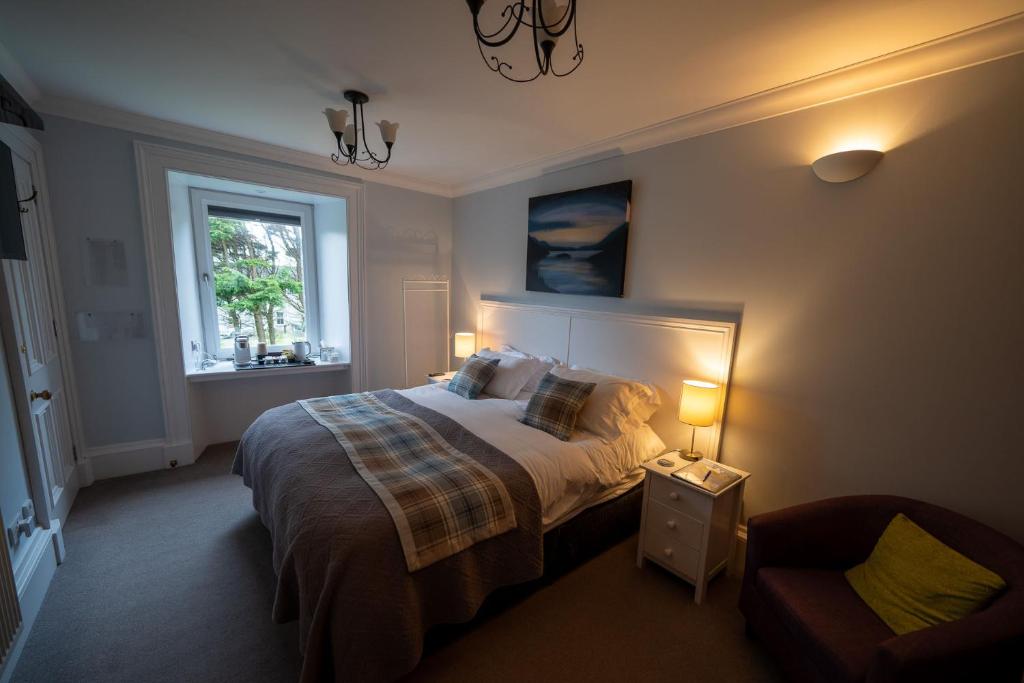 a bedroom with a bed and a chair and a window at Two Harbours Guest House in Scalpay