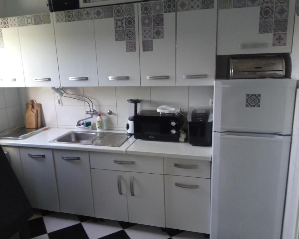 a kitchen with white cabinets and a sink and a refrigerator at Panta rhei in Razvala