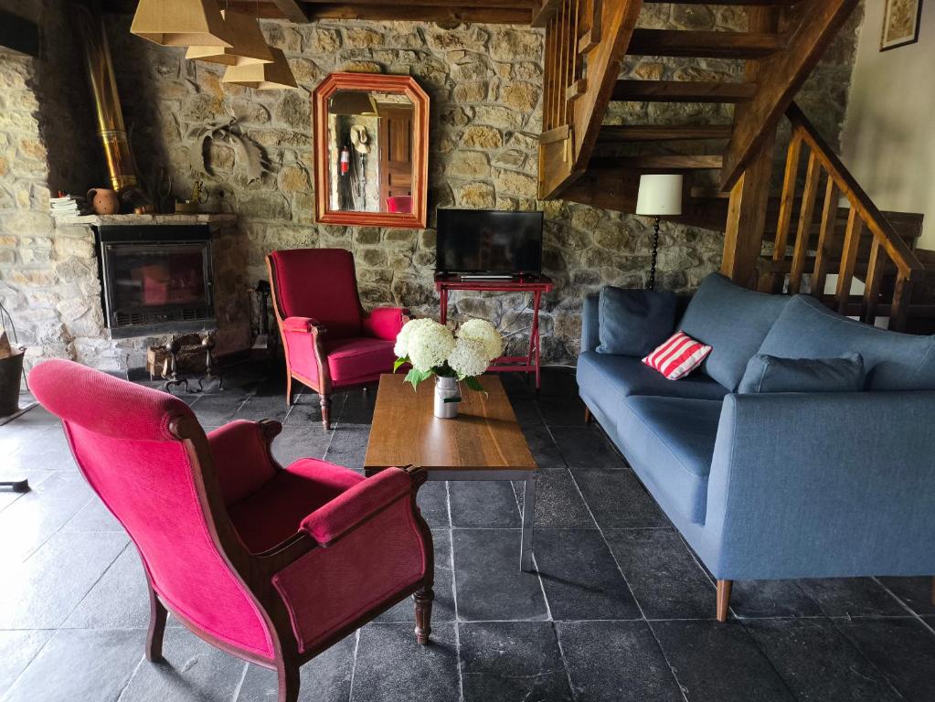 a living room with a blue couch and pink chairs at Casa Maruxela in Borines