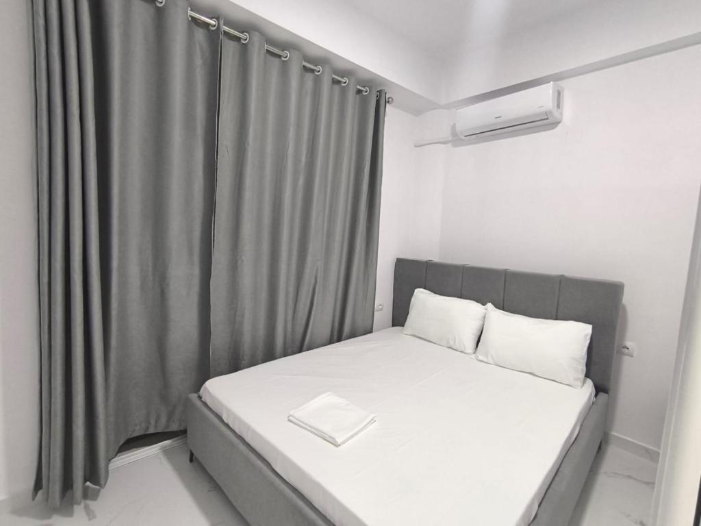 a small bedroom with a bed with a gray curtain at Delvina Central Rooms by Mira in Delvinë