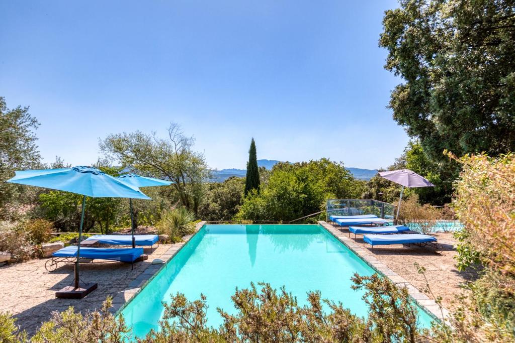 una piscina con sillas y sombrillas en Gîte Mas Grand Bosc Micocouliers, en Notre-Dame-de-Londres