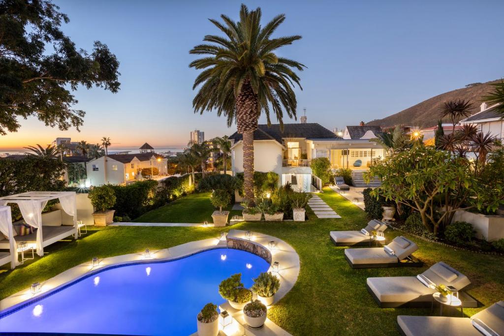 a backyard with a swimming pool and a palm tree at The Clarendon - Fresnaye in Cape Town