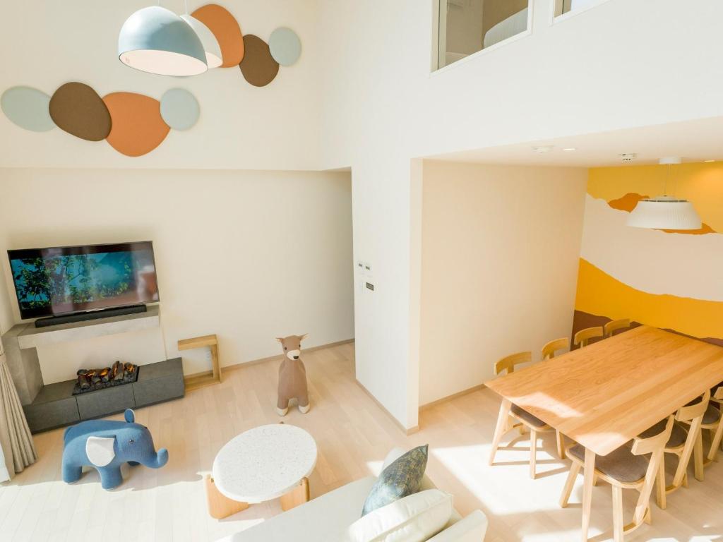 ein Wohnzimmer mit Tisch und Stühlen und einem Fernseher in der Unterkunft Rakuten STAY VILLA Yatsugatake - 104 Family Room Pets Friendly - in Hokuto