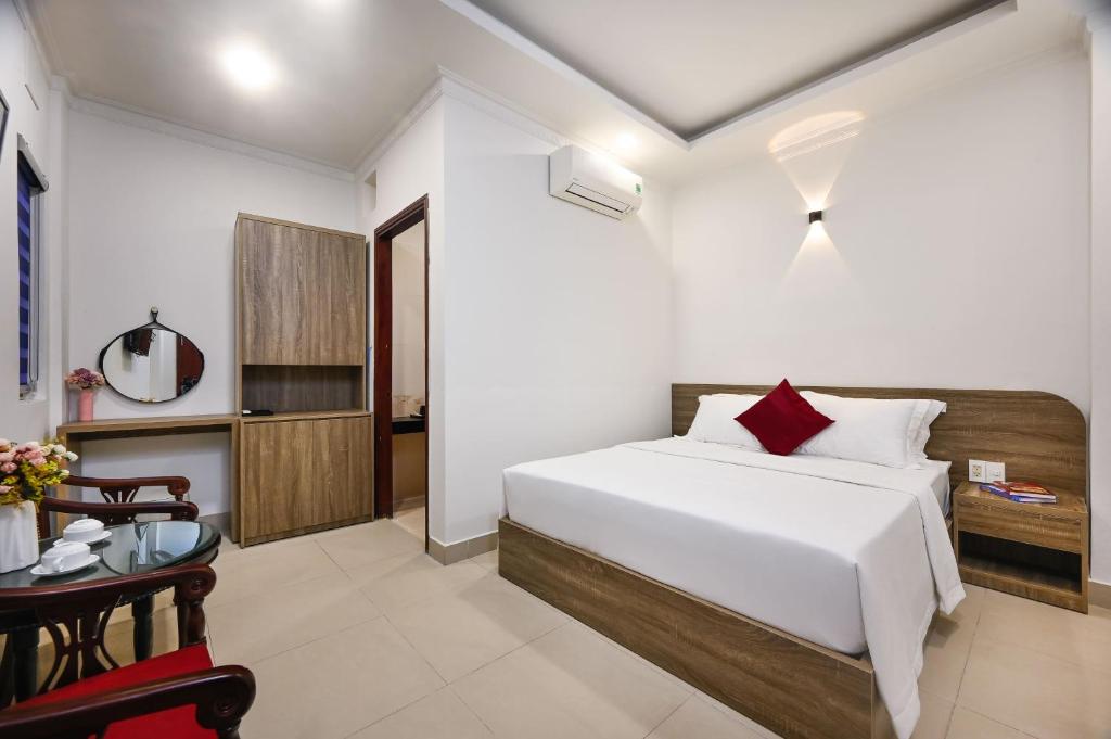 a bedroom with a white bed and a table and a chair at Khách sạn Trung Mai-Tân Bình in Ho Chi Minh City