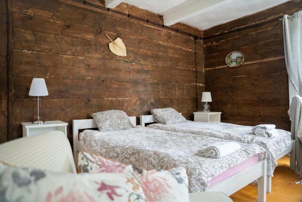 two beds in a room with wooden walls at Siedlisko nad Wieprzem in Kośmin