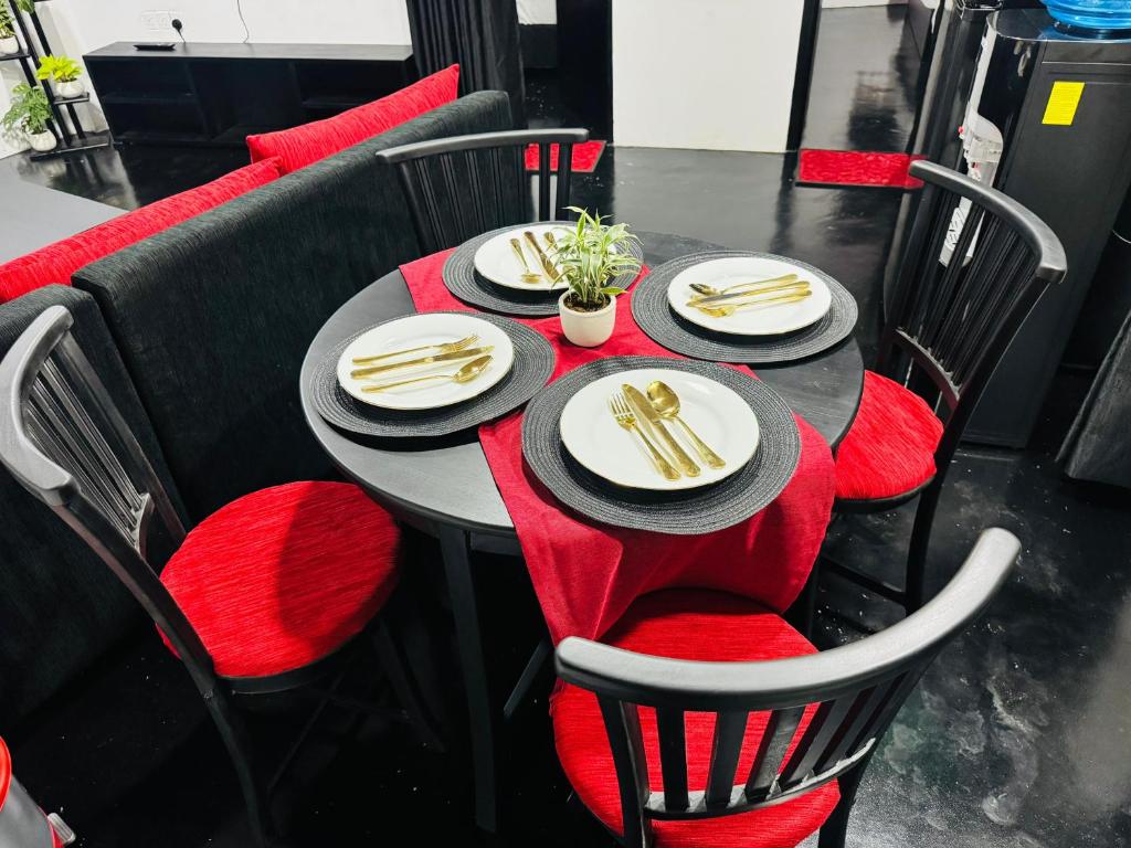 a black table with red chairs and plates and napkins at Cinnamon Villa - Ambuluwawa in Gampola