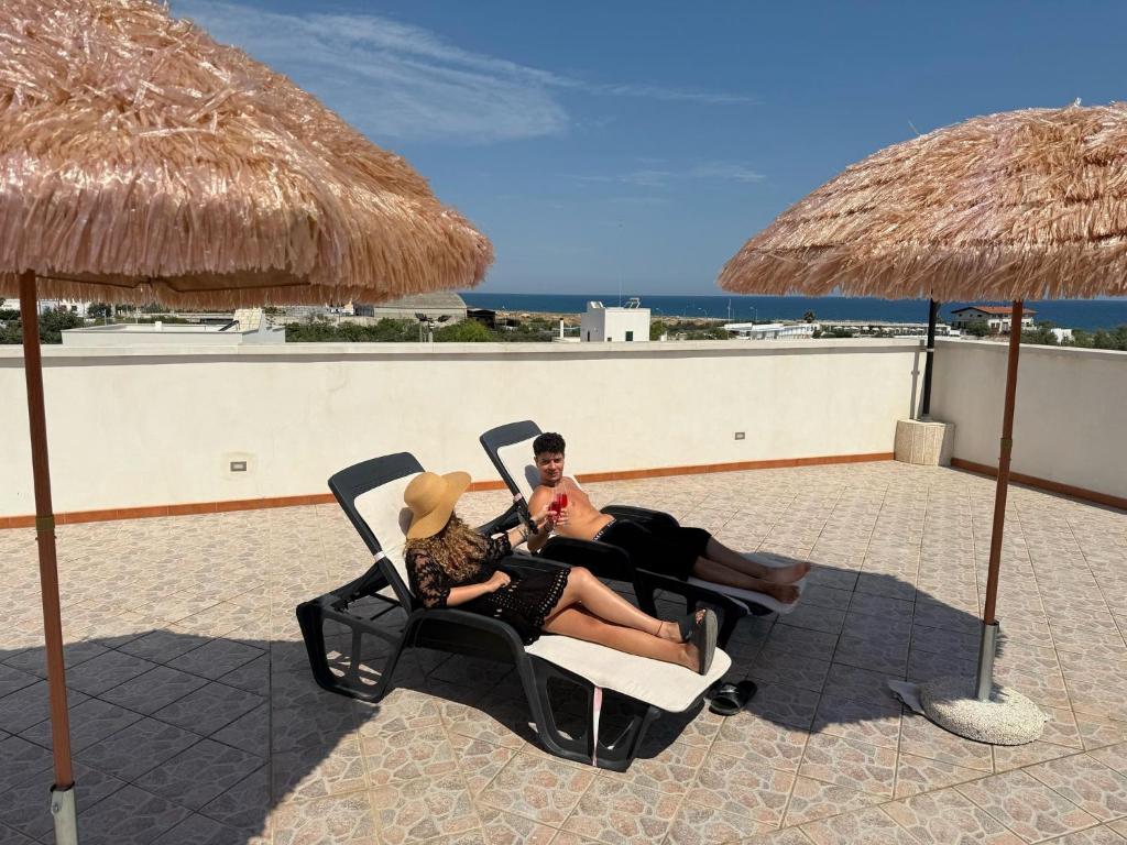 a man and woman sitting in chairs on the beach at Al Vecchio Frantoio al Mare in Monopoli