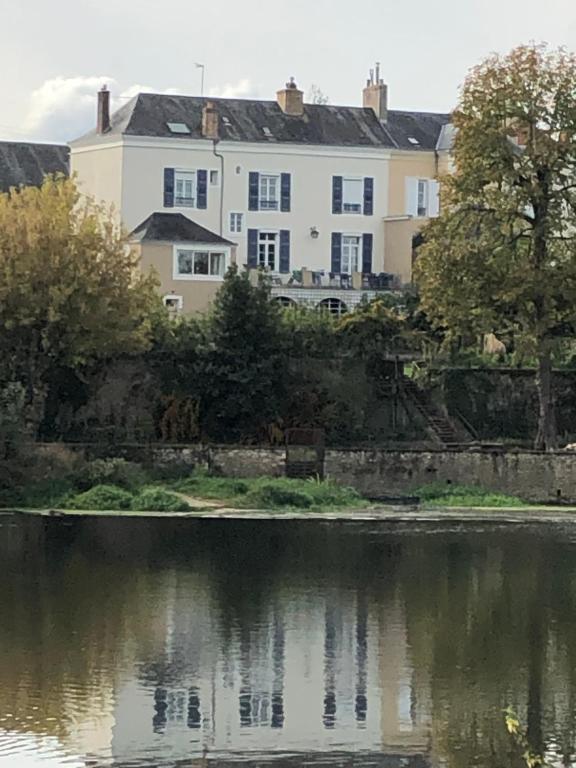 ein großes weißes Haus neben einem Wasserkörper in der Unterkunft Chez Delphine et Bob -Ancienne Maison de Tanneurs in La Suze-sur-Sarthe