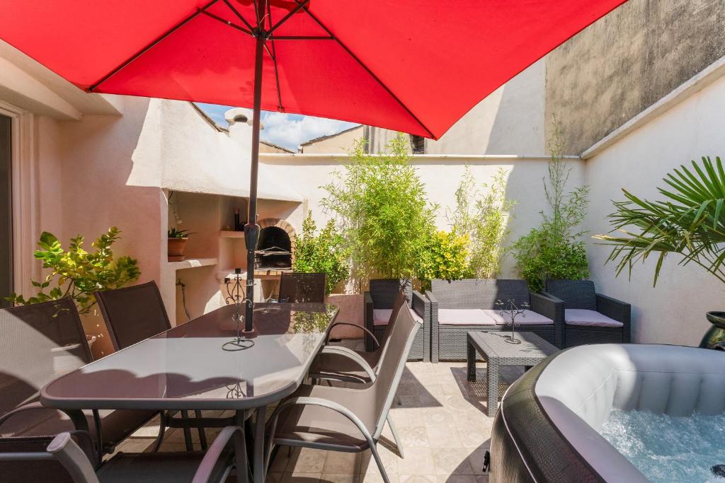 d'une terrasse avec une table et un parasol rouge. dans l'établissement La Bonbonnière Gîte De Charme, à Malaucène