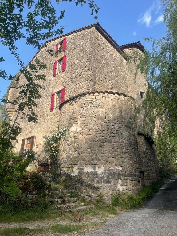 un vieux bâtiment en briques avec des fenêtres rouges dans l'établissement Le Château de Sorgues, à Cornus