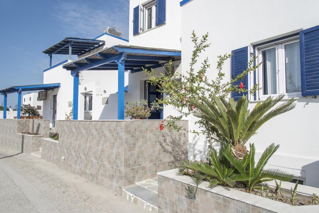 a white house with blue shutters and plants at Heliovasilema Studios in Pollonia