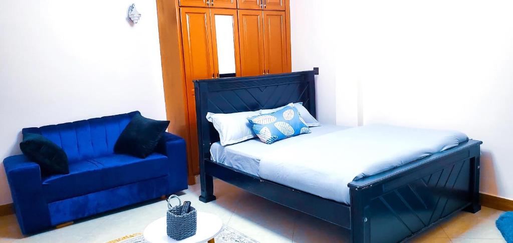 a bedroom with a bed and a blue chair at Ayan homes in Namulanda