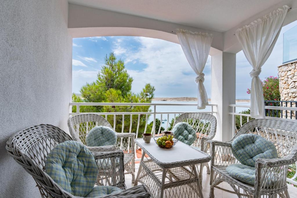 - une terrasse couverte avec des chaises en osier et une table sur un balcon dans l'établissement Sunset, à Kustići